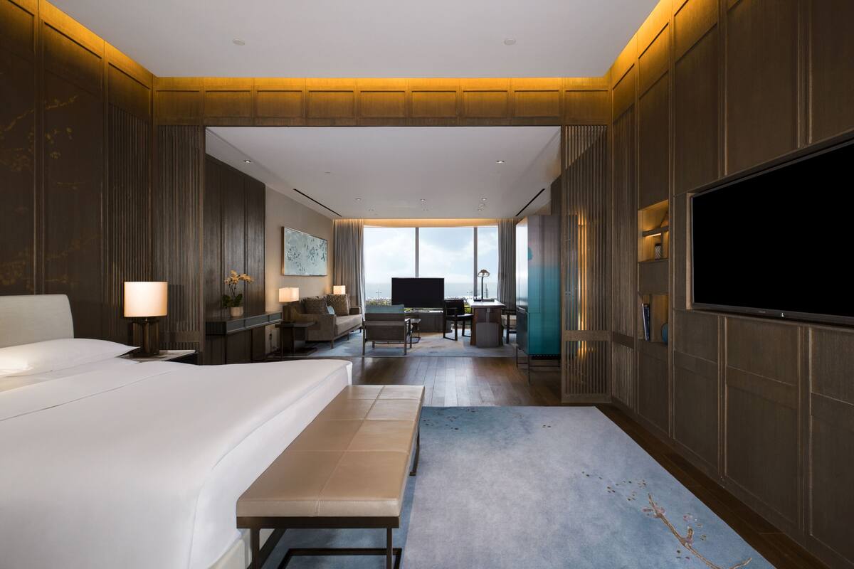 Habitació d'hotel moderna amb un llit gran, una taula de treball, una televisió i vistes a la ciutat.