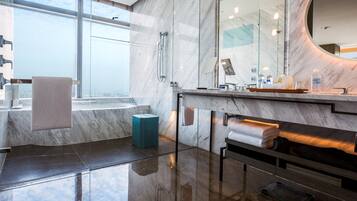 Un baño moderno con un espejo grande, una bañera y un tocador con un perchero para toallas.
