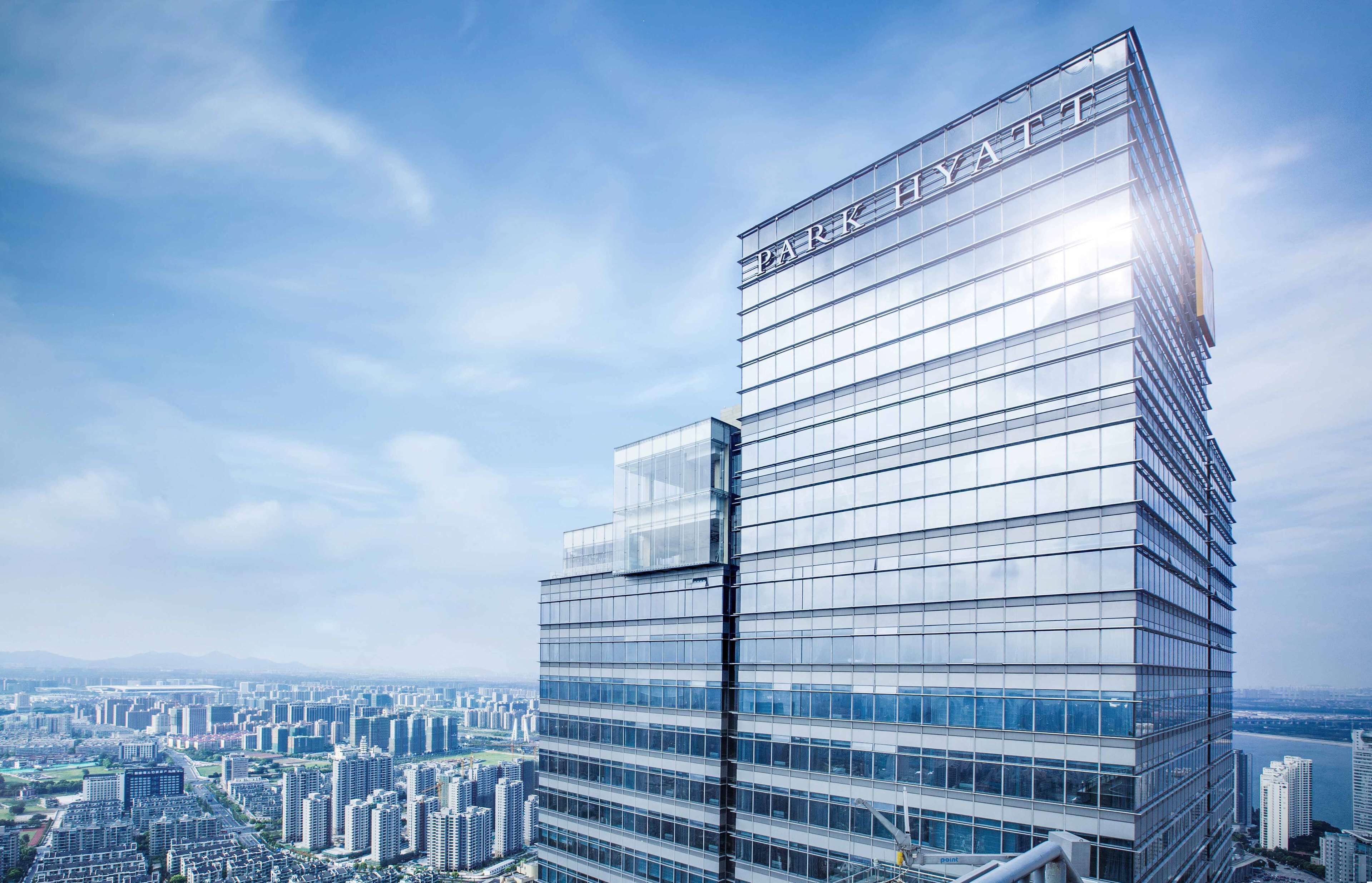 A modern high-rise hotel with a glass facade and the name 'Park Hyatt' on the top.