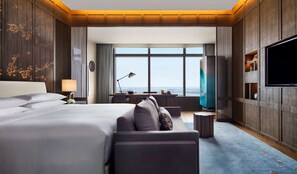 Une chambre d’hôtel avec un grand lit, un canapé, un bureau, une télévision et une vue sur la ville.