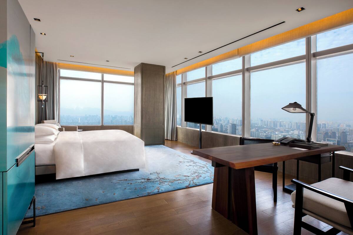 Habitació d'hotel moderna amb un llit gran, una taula de treball i vistes a la ciutat.