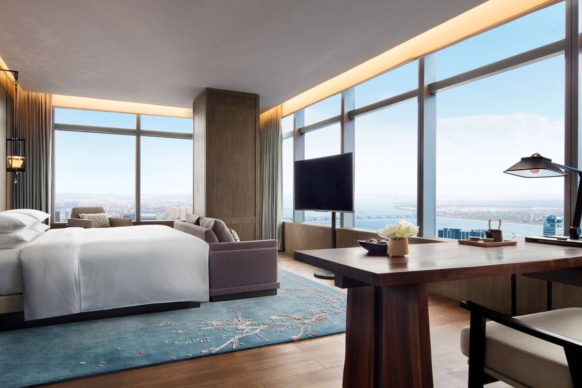 Habitació d'hotel moderna amb un llit gran, una taula de treball i una televisió.