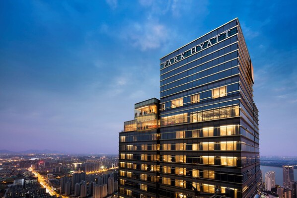Un hôtel moderne de grande hauteur, reconnaissable à son grand panneau « PARK HAYT », avec de nombreux étages et une vue sur le paysage urbain en arrière-plan.