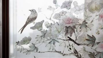 A room with a large window featuring a traditional Chinese-style floral and bird painting.