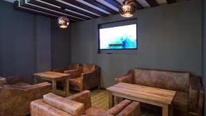 A room with leather sofas, wooden tables, and a flat-screen TV mounted on the wall. - Premier Inn London Brixton (London)