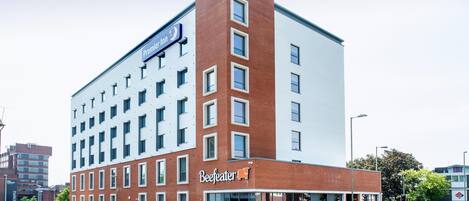 Ein mehrstöckiges Hotel mit einem gut sichtbaren 'Premier Inn' Schild, einem 'Beefeater' Restaurant und einem modernen architektonischen Design.