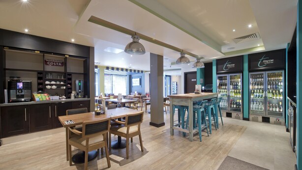 A modern cafe with wooden furniture, a bar area, and refrigerated display cases.