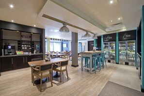Un café moderno con mobiliario de madera, una barra y vitrinas refrigeradas.