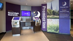 A check-in area with a digital kiosk, a monitor, and a reception desk at Premier Inn London Tottenham Hale.