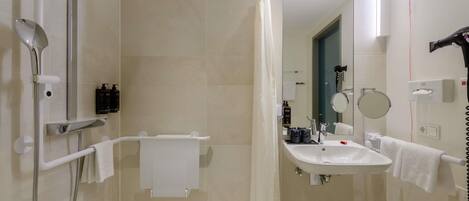 A modern bathroom with a shower, a sink, a mirror, and a hairdryer.