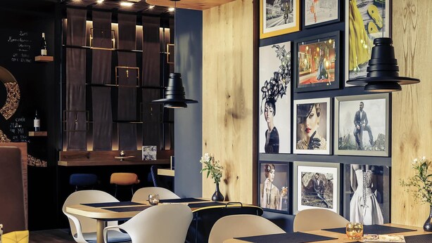 Un intérieur de restaurant moderne, agrémenté d’éléments en bois, de meubles contemporains et d’œuvres d’art encadrées qui ornent les murs.
