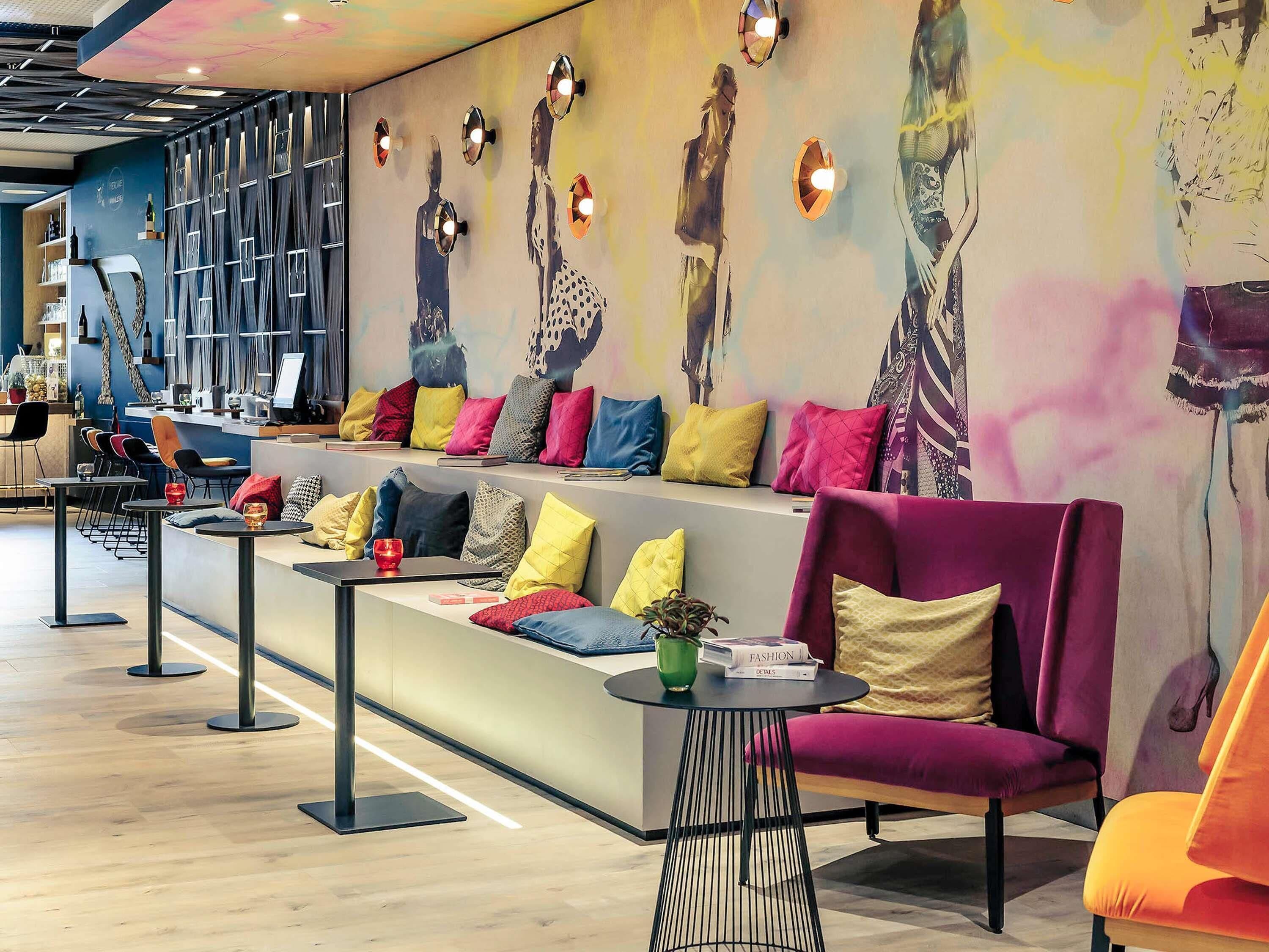 A modern lounge area with a long bench, colorful cushions, and a bar counter with seating.