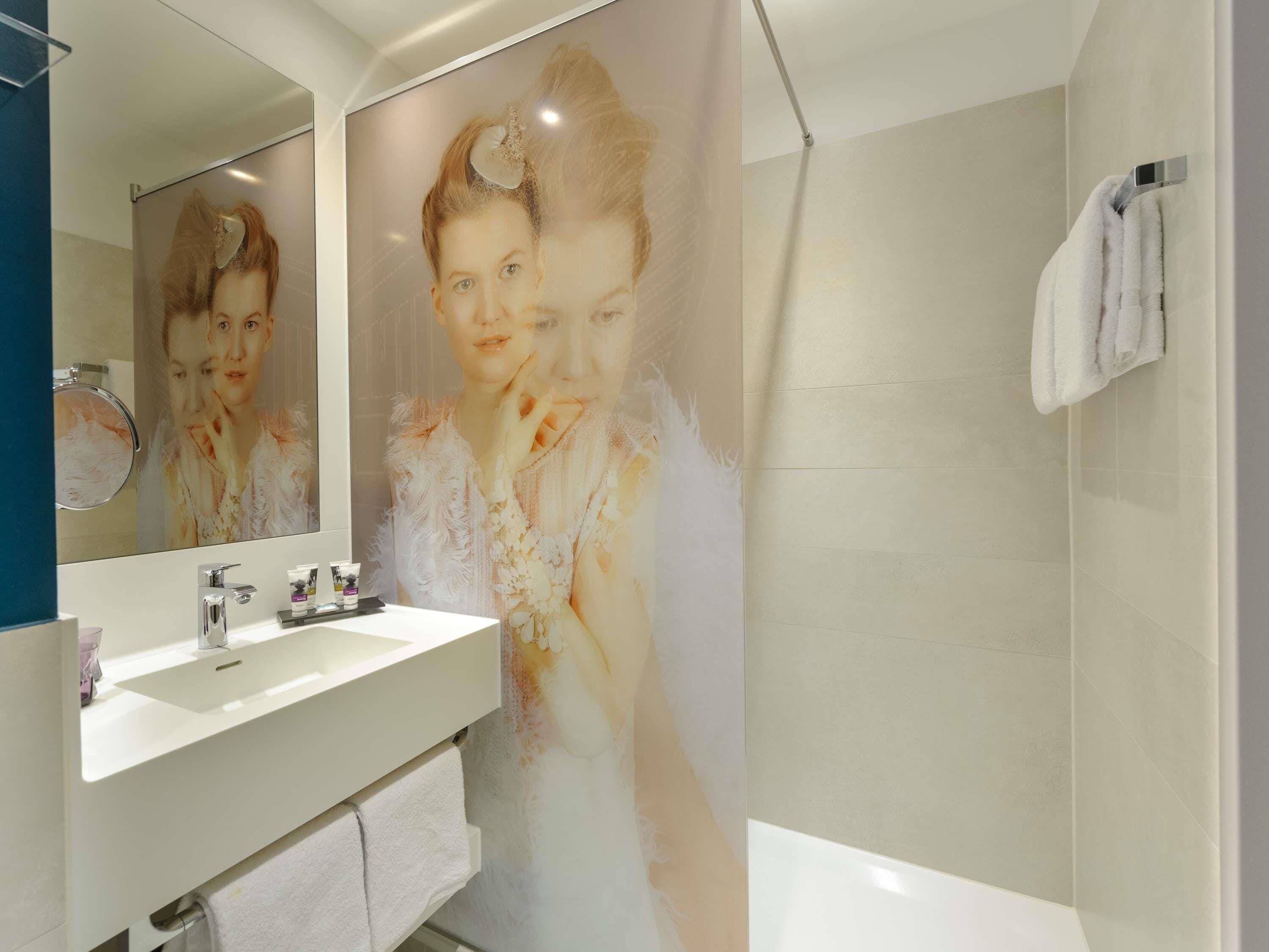Un baño con un espejo grande, un lavamanos y una ducha.