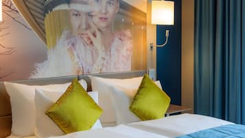 Ein Hotelzimmer mit Bett, Kissen, einer Wandleuchte und einem Gemälde.