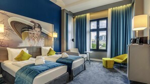 Une chambre d’hôtel avec deux lits, un bureau, une chaise et une grande fenêtre avec des rideaux.