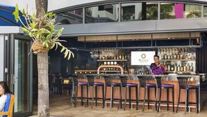 An outdoor bar area with a counter, multiple bar stools, and a bartender. - Mercure Yangon Kaba Aye (Yangon)