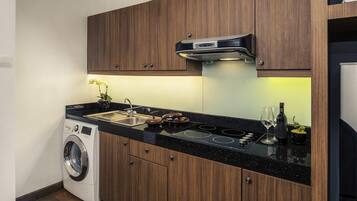 Una cocina moderna con armarios de madera, horno empotrado, lavamanos y lavadora.