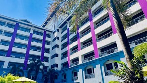 A hotel with a swimming pool, palm trees, and a multi-story building with purple accents. - Mercure Yangon Kaba Aye (Yangon)