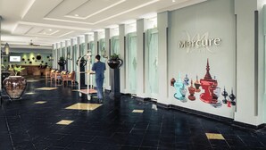 A hotel lobby with a reception desk, seating area, and a wall with a mural of temple spires. - Mercure Yangon Kaba Aye (Yangon)
