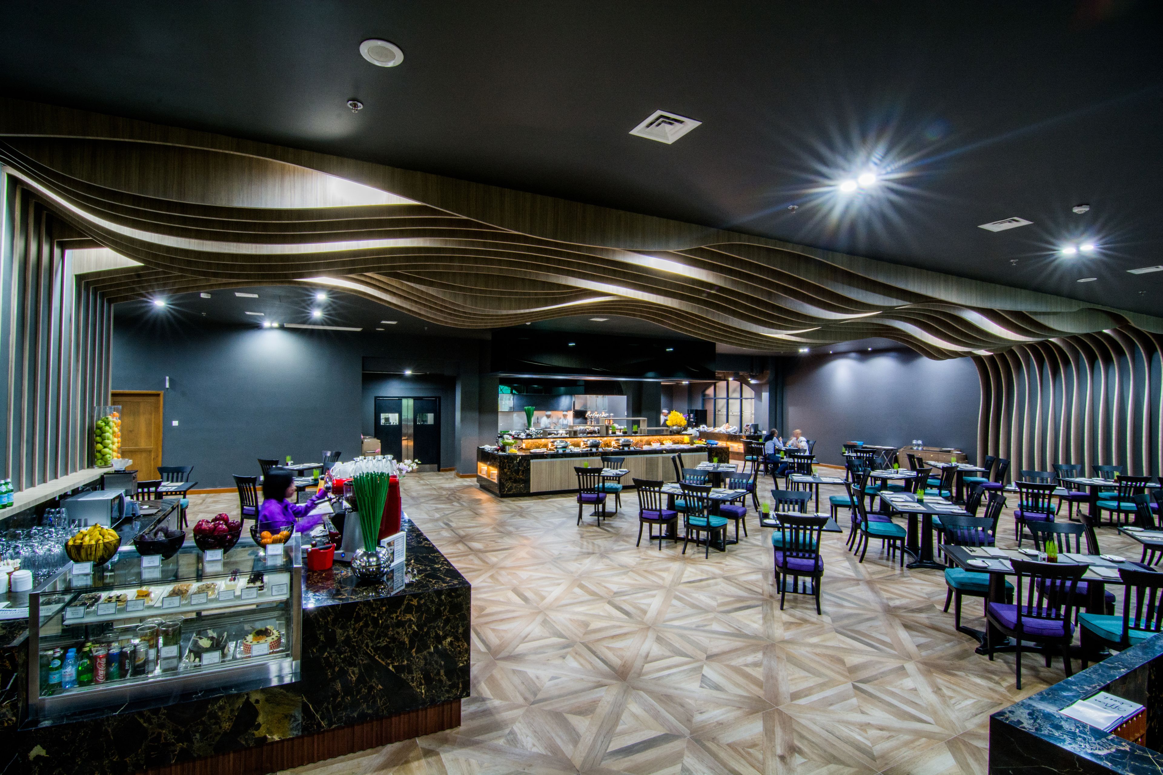 Un restaurante moderno con barra central, varias zonas de estar y suelo estampado.