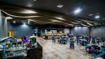 Un restaurante moderno con barra central, varias zonas de estar y suelo estampado.
