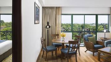 A room with a balcony, a dining table with chairs, a sofa, and a lamp.