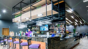 A bar area with multiple seating options, a bartender, and a variety of bottles and glasses. - Mercure Yangon Kaba Aye (Yangon)