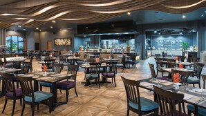 A modern restaurant with a central bar, multiple dining tables, and chairs. - Mercure Yangon Kaba Aye (Yangon)