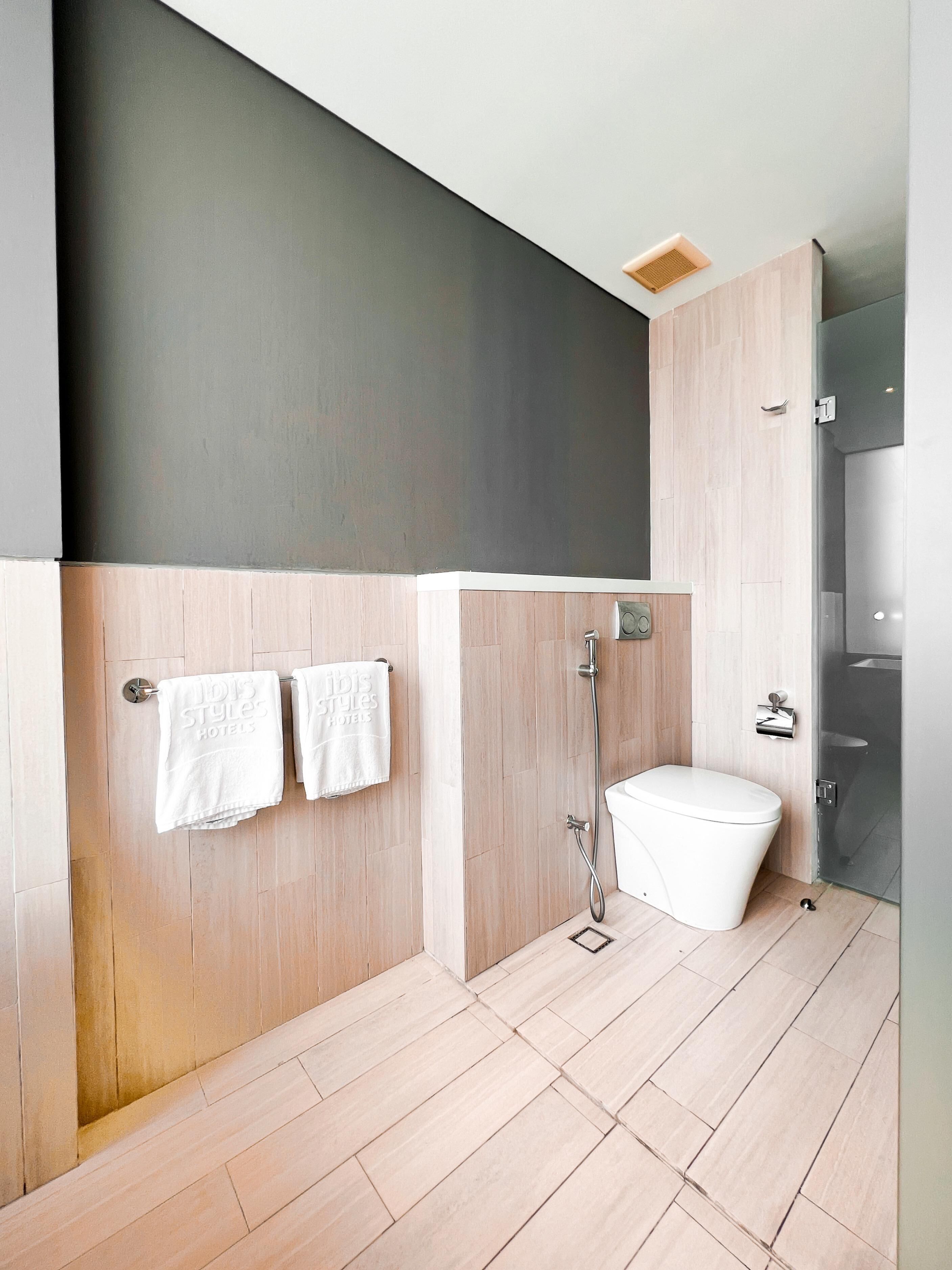 A modern bathroom with a shower, toilet, and a towel rack with two towels.