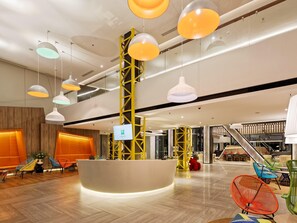 A modern lobby with a reception desk, colorful chairs, and a staircase. - Ibis Styles Batam Nagoya (Batam)