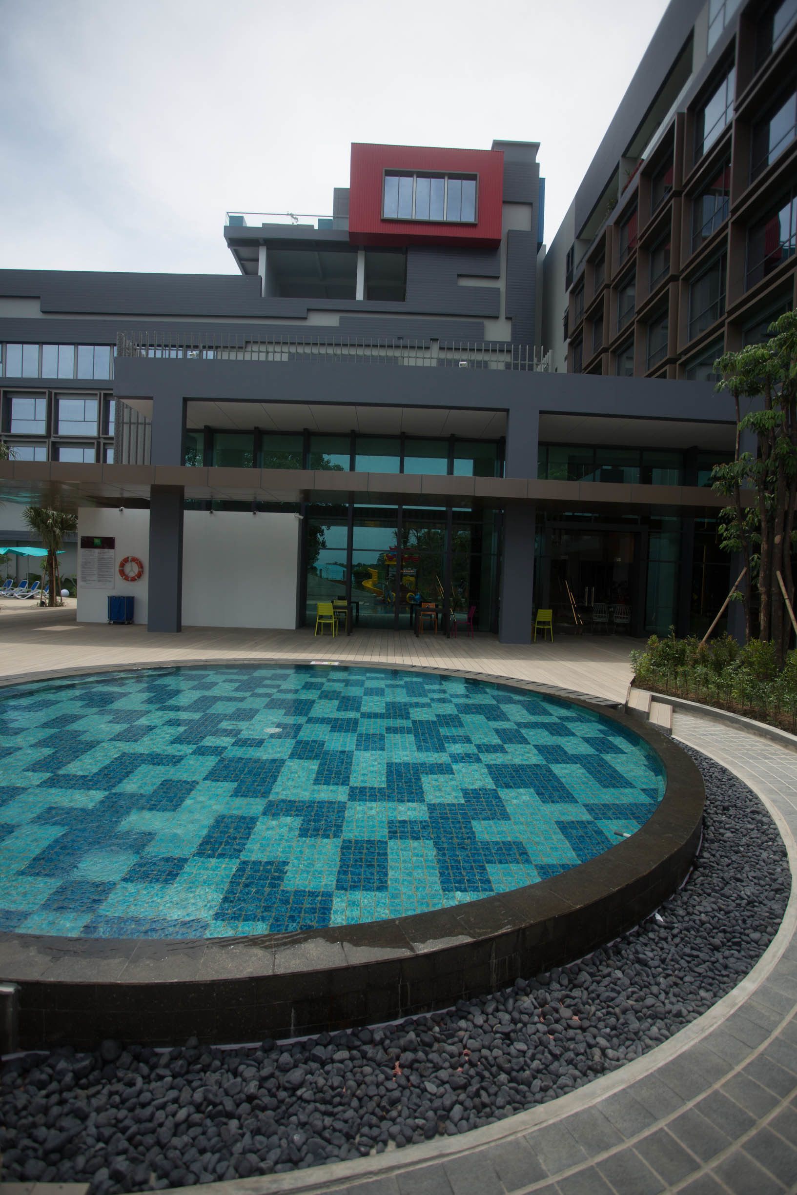 Un edificio moderno con piscina que destaca por un diseño de mosaicos azules y turquesa.