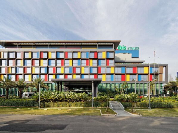 A modern hotel with a colorful facade, a covered entrance, and a landscaped front garden. - Ibis Styles Batam Nagoya (Batam)