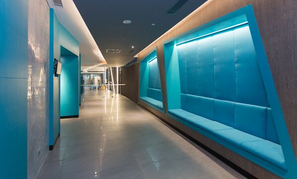 A corridor with blue seating areas and a modern design. - Ibis Styles Batam Nagoya (Batam)