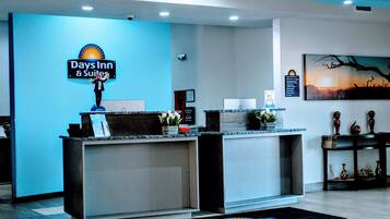 Una reception con il cartello 'Days Inn & Suites', un certificato incorniciato e un dipinto del tramonto.