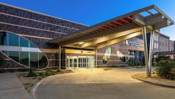 A modern building with a curved facade, large glass entrance, and a covered walkway.