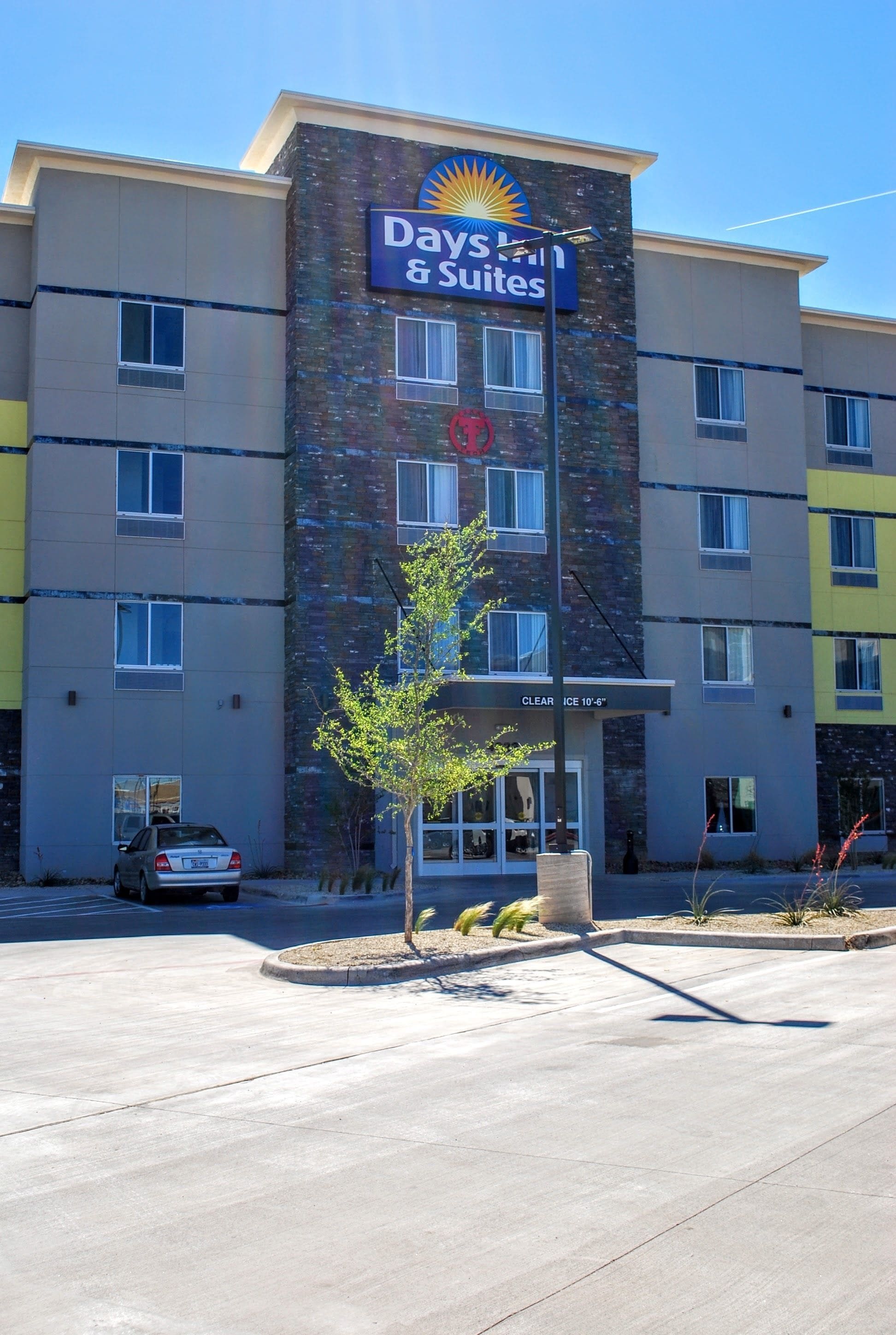 Een meerlaags hotel met een 'Days Inn & Suites' bord, duidelijke bewegwijzering en een parkeerplaats.
