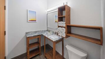 A bathroom with a wooden vanity, marble countertop, and a toilet.
