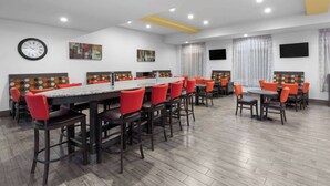 A conference room with a long table, red chairs, and a clock on the wall.
