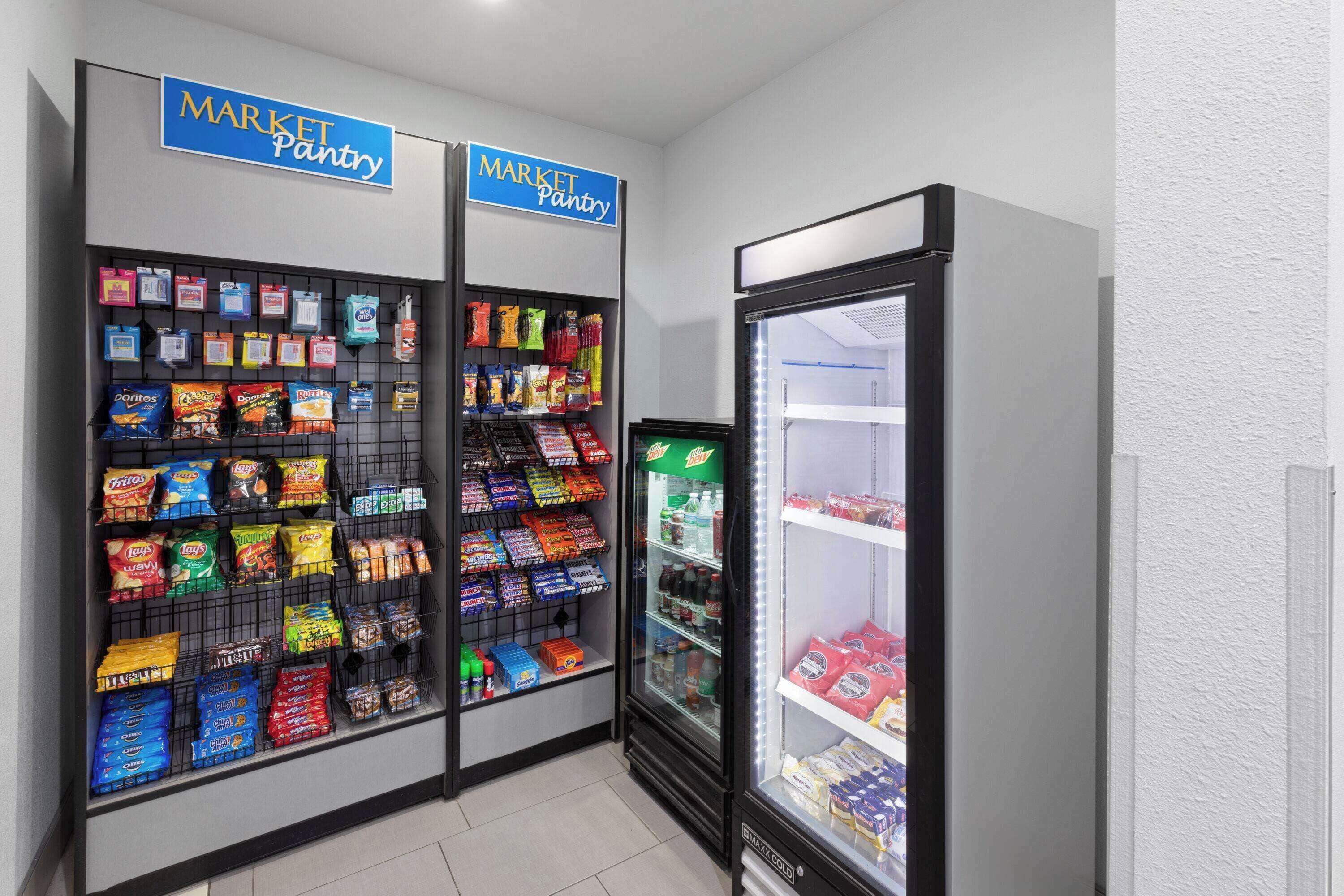 A market pantry with snack and drink shelves, and a refrigerated section.