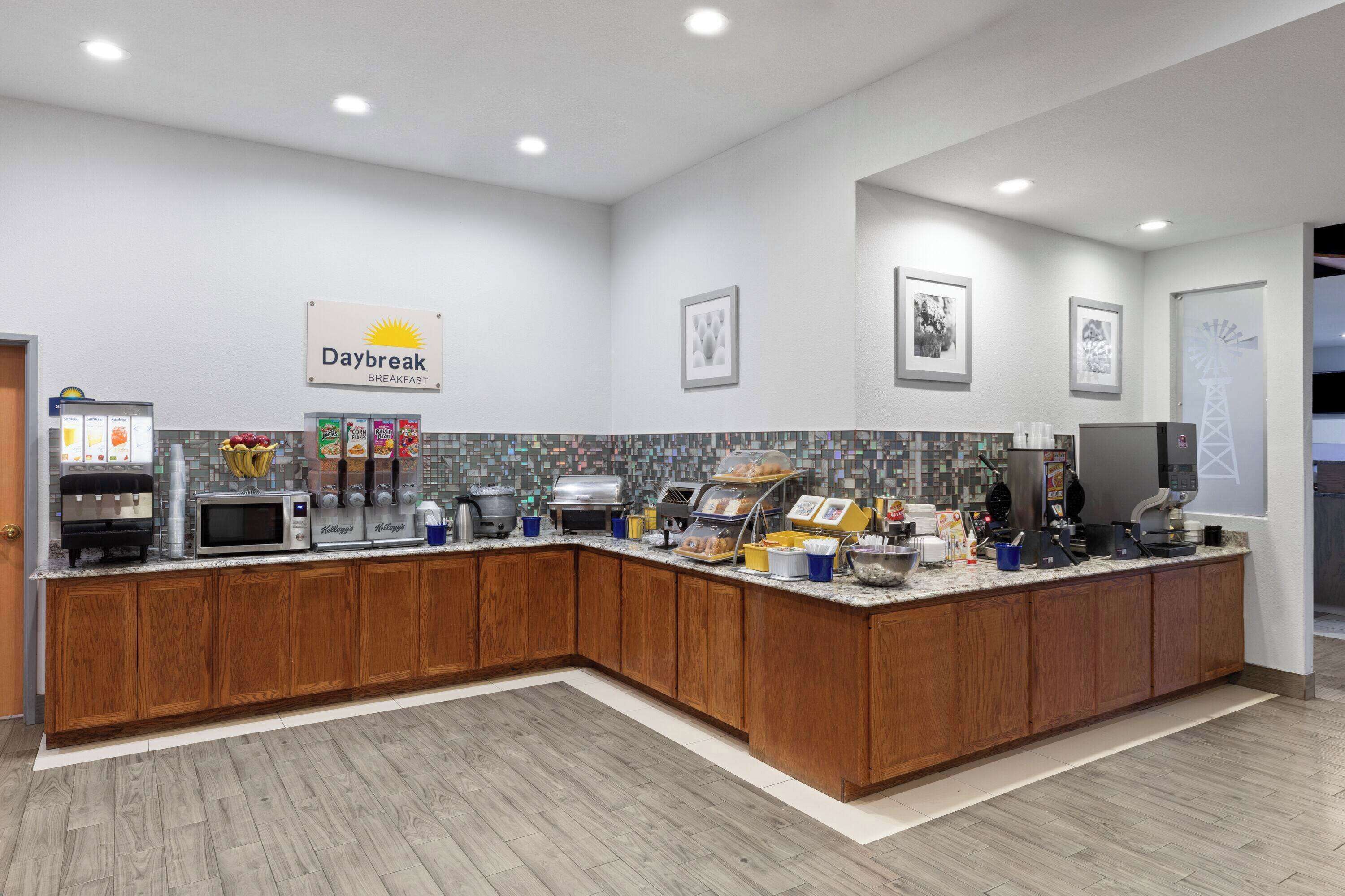 A modern kitchen with a breakfast bar, equipped with a coffee machine, microwave, and various food items.