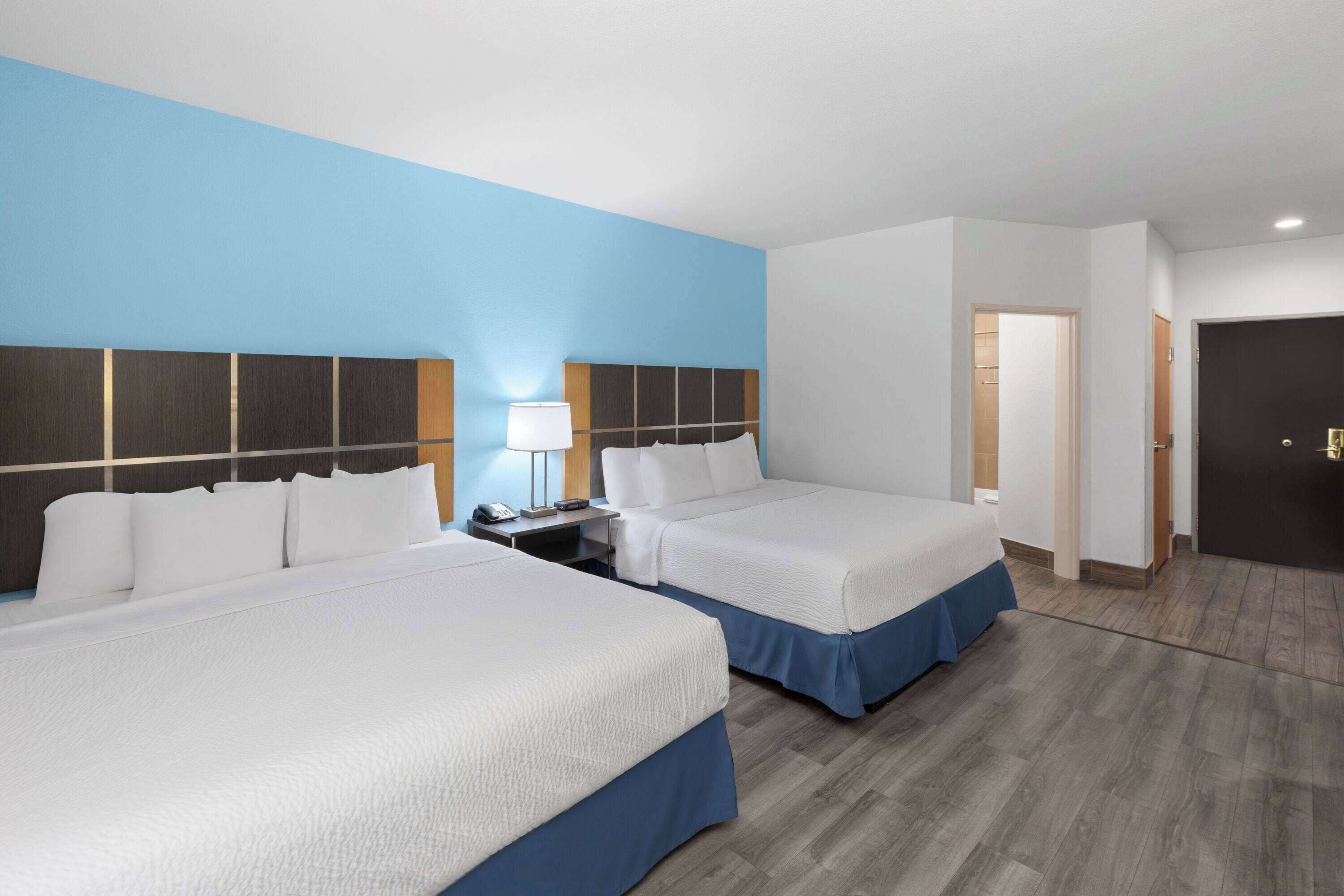Ein Hotelzimmer mit zwei Betten, einem Nachttisch, einer Lampe und einer Tür.