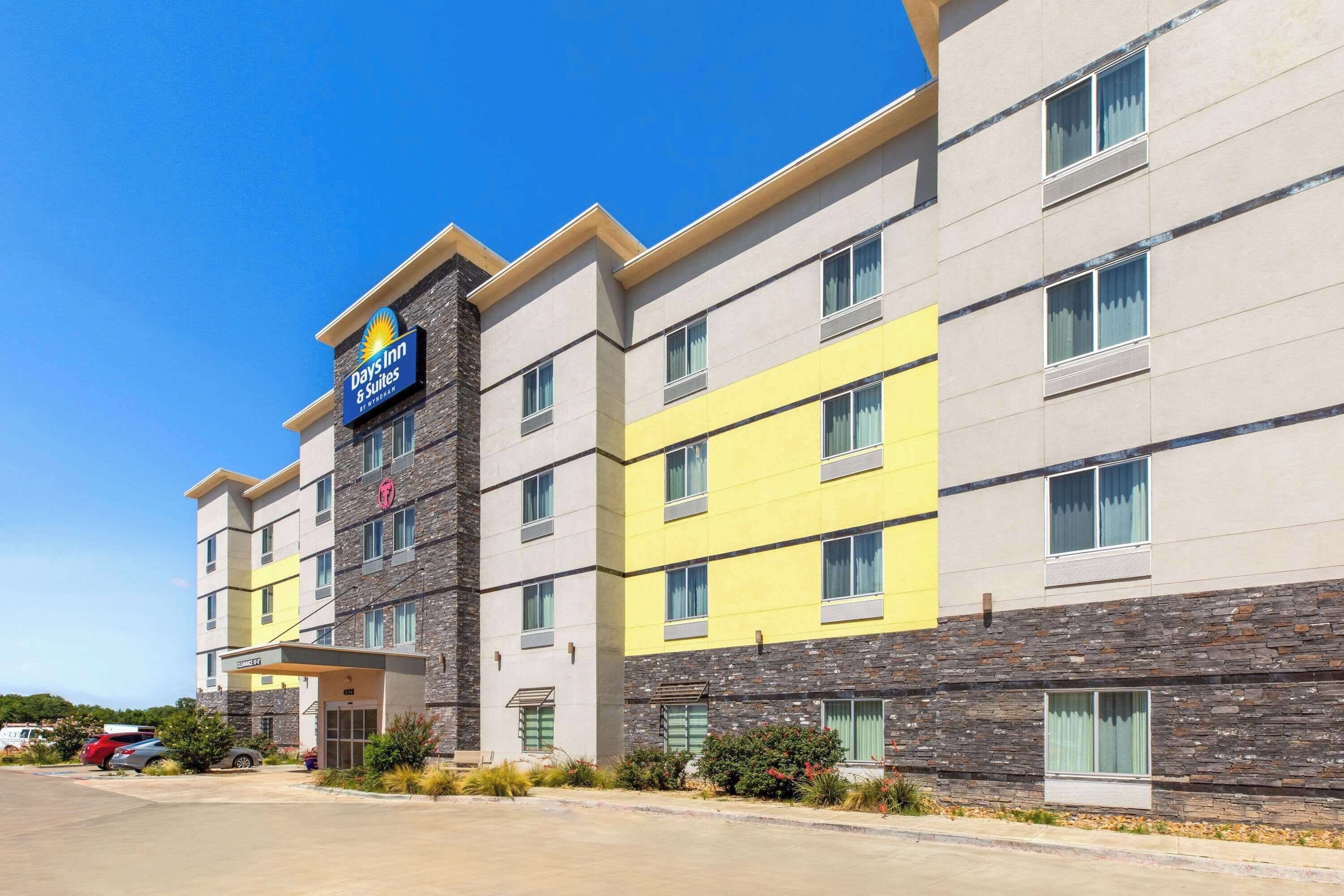 A Days Inn & Suites building with a stone facade, multiple windows, and a clear sky.