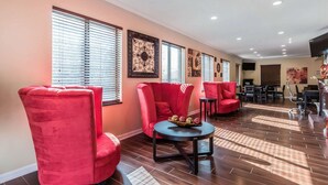 Amplia sala de estar con sillones tapizados en rojo, una mesa redonda con un centro de mesa decorativo y piso de madera.