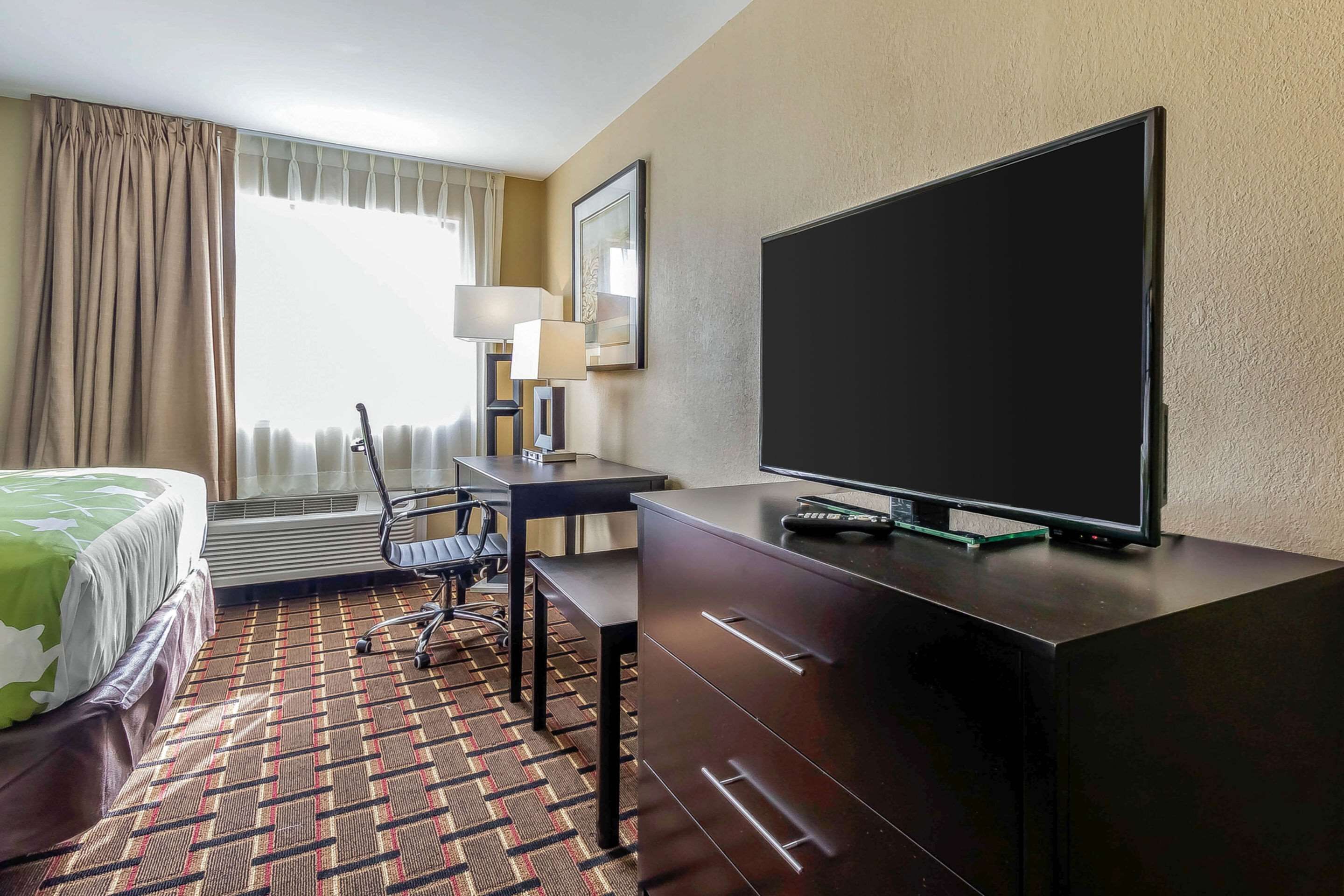 A hotel room with a bed, a desk, a television, and a chair.