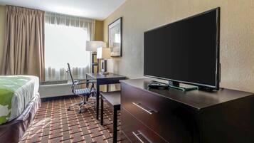 A hotel room with a bed, a desk, a television, and a chair.