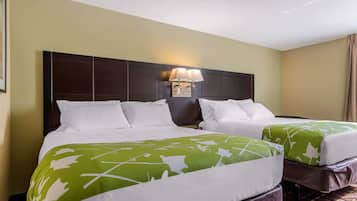 A hotel room with two beds, a headboard with a light fixture, and a patterned bedspread.