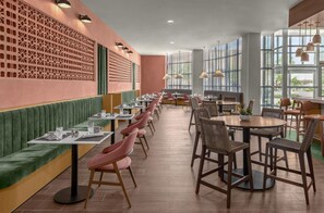 A restaurant with booths and tables, a patterned wall, and large windows. - DoubleTree by Hilton Midland West Loop I-250 (Midland)