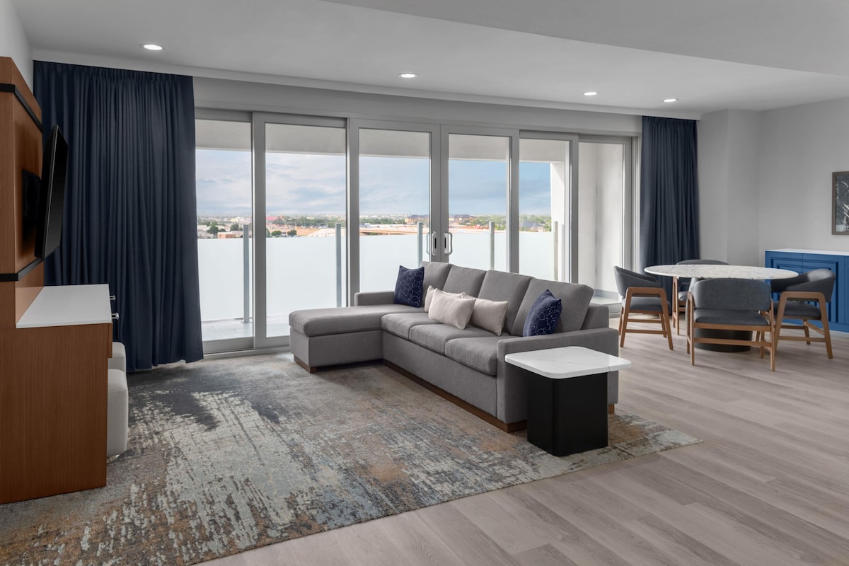 A modern living room with a grey sectional sofa, a coffee table, and a view of the water.
