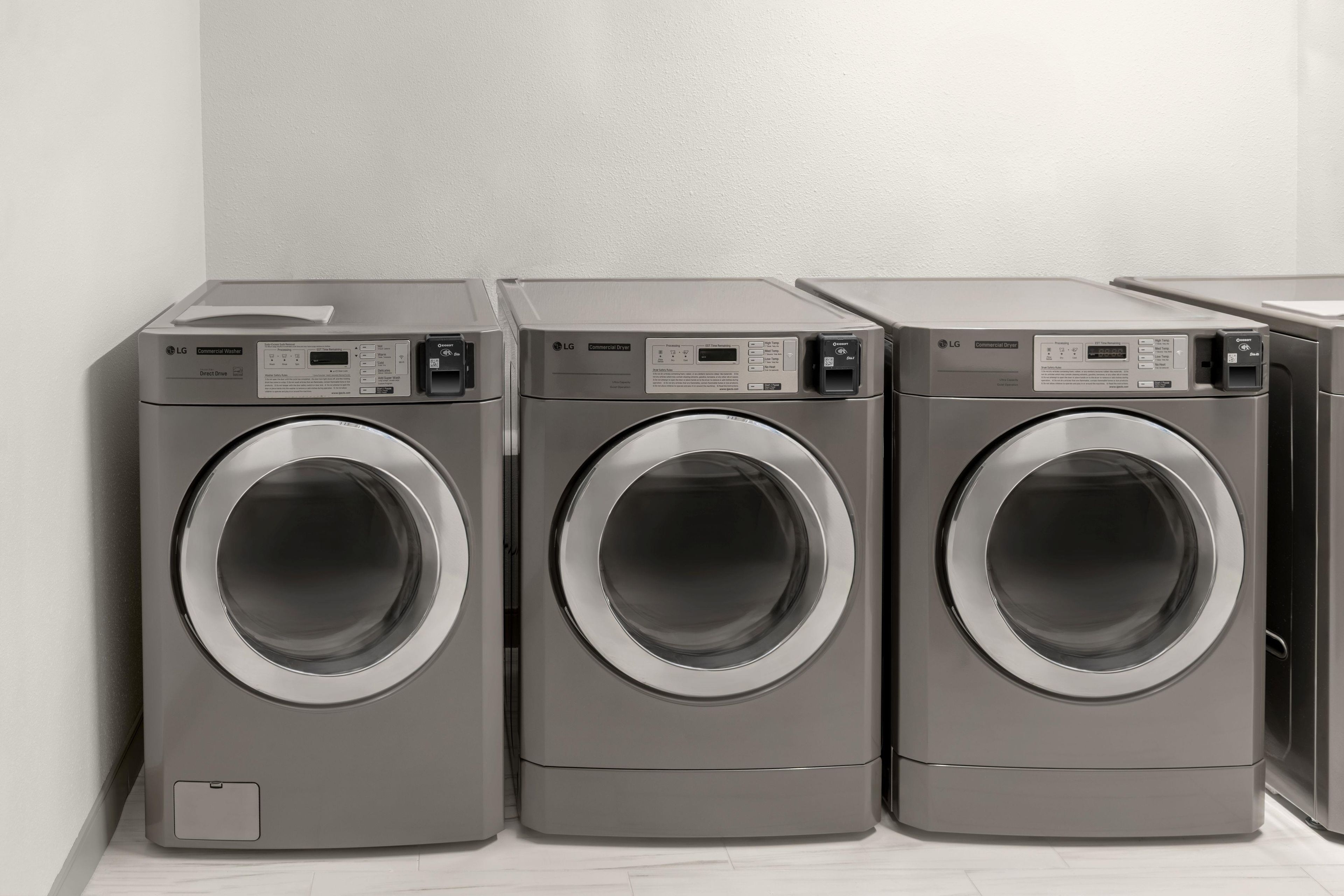 Three commercial washers with control panels, placed against a plain wall.