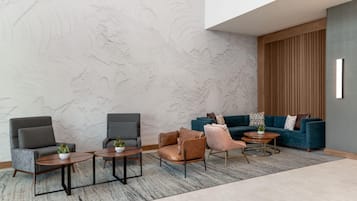 A modern lounge area with seating arrangements, including sofas and chairs, a patterned wall, and a wooden panel accent.